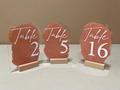 three clear acrylic table numbers on wooden bases