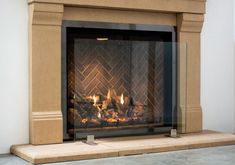 a fireplace with a fire in it sitting on top of a stone floor next to a white wall