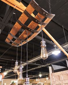 some light fixtures hanging from the ceiling in a store with wooden planks and lights