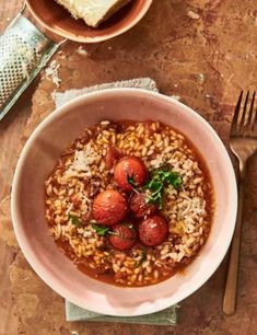 a bowl filled with rice and strawberries on top of a table next to silverware