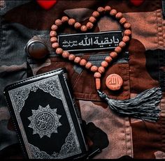 the rosary, book and islamic prayer beads are laid out on top of camouflage cloth