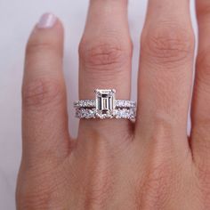 a woman's hand with an engagement ring and wedding band on her left hand