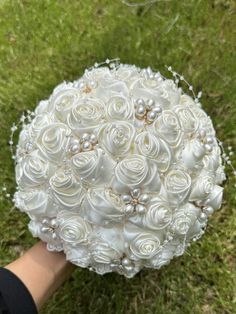 a bridal bouquet is being held in the air by someone's hand on some grass