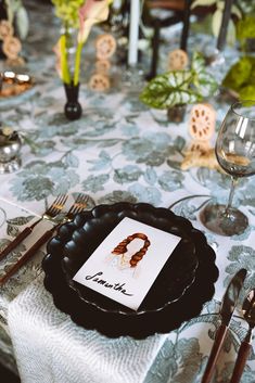 the table is set with black plates and silverware