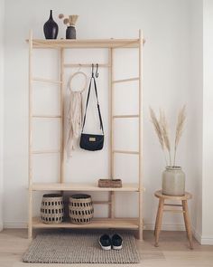 a wooden shelf with two bags and shoes on it next to a stool, vases and plant