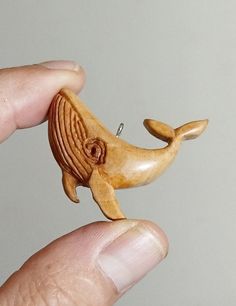 a hand holding a small wooden whale ornament