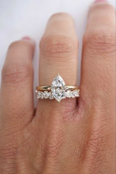 a woman's hand with a diamond ring on top of her finger and an engagement band