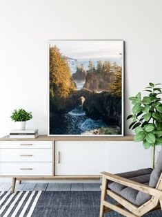 a living room with a chair, plant and large poster on the wall above it