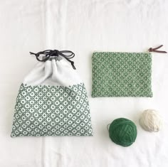 two balls of yarn sitting next to a green and white bag