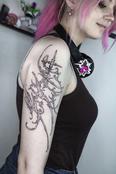 a woman with pink hair has a tattoo on her arm