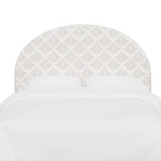 a white bed with an intricate headboard and pillows on it's back side