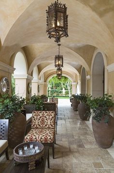 the hallway is lined with potted plants and chandeliers