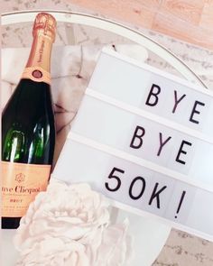 a bottle of champagne sitting on top of a table next to a sign that says bye bye 50k