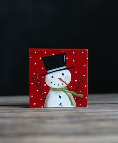 a wooden block with a snowman painted on it