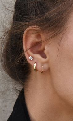 a close up of a person's ear wearing an earring with a flower on it