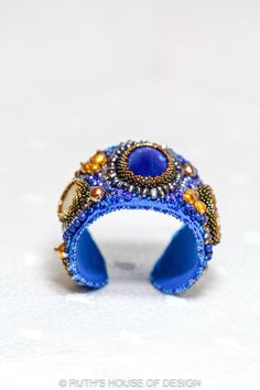 This One of a Kind, Hand embroidered 'Royal Attitude' Couture Cuff Bracelet was  so much fun to design for you.  I fell in love with the Royal Blue Focal Bead and knew I had to match it with Gold accents.  Several Yellowish Jasper stones were strategically placed and accented with Golden Japanese Seed Beads.  Lapis Lazuli Beads were used for color enhancement and Lots of Crystals add Sparkle and Attitude.  Fresh Water Pearls were also added to this very Regal piece of Wearable Art.  Each Bead is Handmade Blue Cuff Bracelet For Formal Occasions, Golden Japanese, Lapis Lazuli Beads, Fresh Water Pearls, Water Pearls, Jasper Stone, Focal Bead, Fell In Love, I Fall In Love