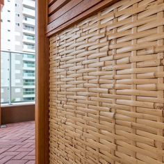 a wall made out of bamboo sticks on a brick floor next to a building with tall buildings in the background