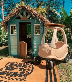 a toy car is parked in front of a small shed with a surfboard on the roof