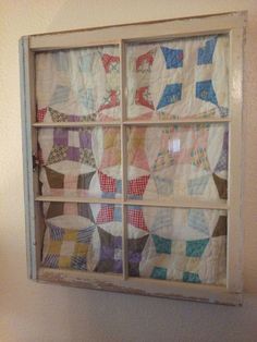 an old window is decorated with colorful quilts