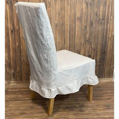 a white chair with a cover on it sitting in front of a wooden wall and floor