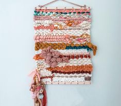 a wall hanging made out of different types of beads and fabric, on a white wall