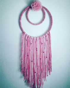 a pink necklace hanging on the wall with a pom - pom attached to it