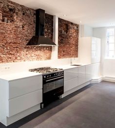 a kitchen with an oven, stove and sink next to a brick wall that has been painted white