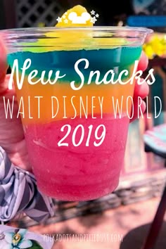 a hand holding a drink with the words new snacks at disney world