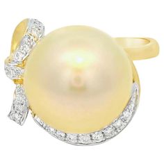 This elegant ring showcases a lustrous 12.6 mm golden South Sea pearl, known for its exceptional size and radiant glow. The pearl is beautifully complemented by a delicate arrangement of diamonds, totaling 0.14 carats, which add a touch of brilliance and sophistication. The diamonds are intricately set in a graceful design around the pearl, enhancing its natural beauty. The ring is crafted from 18-karat yellow gold, providing a warm and luxurious backdrop that perfectly complements the golden pe Sapphire Cocktail Ring, Golden South Sea Pearls, Pearl And Diamond Ring, Gold Cocktail, Gold Cocktail Ring, Diamond Cocktail Rings, Sea Pearls, South Sea Pearls, Modern Ring