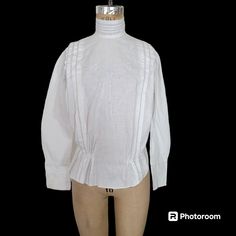 Another 1900s cotton linen Edwardian blouse. 1900s. Button back with high neck and long sleeves. The front of the bodice is embroidered with a floral pattern in a very pale (likely faded) blue. I didn't capture the distinction very well, but I hope it's visible enough on the close-up.  The high neck collar has a small buttonhole at the top on one side but no signs of a button being on the other side.  I've decided to not add a button since some are concerned mostly with the size of the neck on these early garments. You can certainly leave it open or add a button if you wish.  Measurements are taken outside of the garment while flat.  Across the front of the bust while flat, just to 18 inches. Shown on a 32-24-33 form with a little room so I would suggest best to fit a 32 to 34 bust. Across Victorian Long Sleeve Tops With Buttons, Victorian Long Sleeve Blouse For Vintage Fashion, Victorian Long Sleeve Cotton Blouse, Long Sleeve Embroidered Blouse, Traditional Fitted Blouse For Daywear, Fitted Traditional Blouse For Daywear, Edwardian Blouse, High Neck Blouse, Linen Blouse