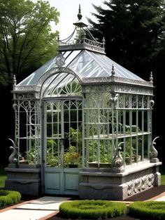 a white metal and glass gazebo in the middle of a garden