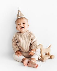 a baby sitting on the floor wearing a birthday hat