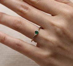 a woman's hand with a diamond and emerald ring