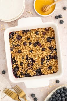 blueberry baked oatmeal in a white dish with honey and spoons