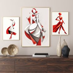 three framed art prints on a wall above a dresser with vases and other items