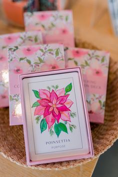 pink poinsettia greeting cards in a basket on top of a wooden table