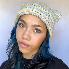 a woman with blue hair wearing a crocheted hat