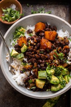 a bowl filled with rice, beans and avocado on top of a table