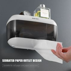 a hand holding a piece of paper in front of a wall mounted toilet paper dispenser