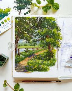 an artist's work with watercolors and paintbrushes on the table