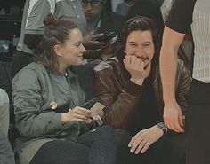 two people sitting next to each other at a basketball game, one is biting into the other's mouth