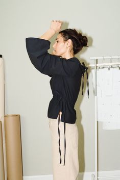 a woman standing in front of a closet holding her hands on her head and looking off to the side