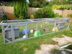 a large chicken coop with several chickens in it's back yard and some grass