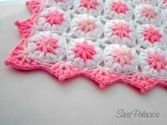 a pink and white crocheted blanket sitting on top of a table