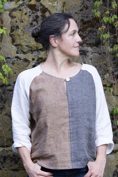 a woman standing in front of a stone wall with ivy growing on it's sides