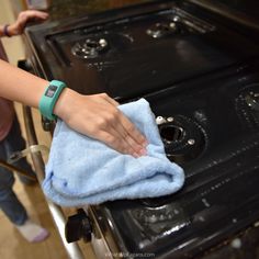 a woman is cleaning an oven with a blue towel and a smart watch on her wrist