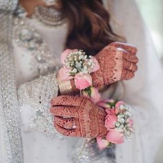 a woman in white dress holding pink flowers and wearing hendids on her hands