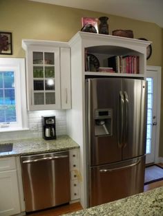 a stainless steel refrigerator in a kitchen with white cabinets and granite counter tops, along with a coffee maker