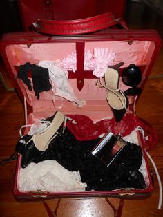 an open red suitcase filled with clothes and shoes on top of a hard wood floor