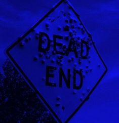 a dead end sign in front of a dark blue sky with trees and clouds behind it